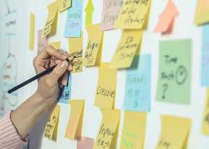 Image of someone writing on post it notes